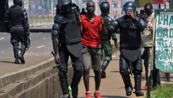 Des policiers guinéens encadrent un manifestant arrêté. Le 14 novembre 2019.