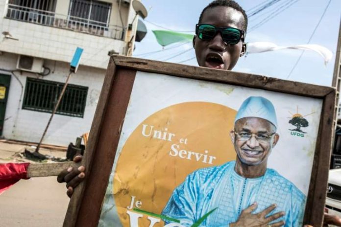 © JOHN WESSELS Un partisan de Cellou Dalein Diallo, principal rival du président guinéen à l'élection du 18 octobre, brandit son portrait à Conakry le 12 octobre 2020