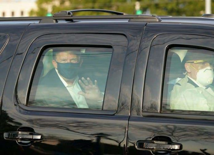 © ALEX EDELMAN © 2019 AFP Le président américain Donald Trump salue ses symathisants depuis la limousine présidentielle lors d'une brève sortie de l'hôpital militaire de Walter Reed à Bethesda, près de Washington, le 4 octobre 2020