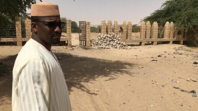 Alpha Ibrahim Ben Essayouti, imam adjoint de la Grande Mosquée de Djingareyber, devant les grilles d'un cimetière abritant trois mausolées, le 23 mars 2021.